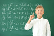 © Pixel-Shot - Little boy with raised index finger near school blackboard in classroom