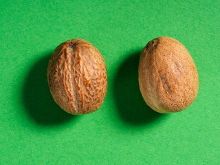 Two nutmegs (Myristica fragrans) on a green background