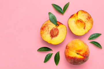 Flat lay composition with peaches. Ripe juicy peaches with green leaves on pink background. Flat lay, top view, copy space. Fresh organic fruit, vegan food. Harvest concept.