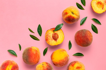 Wall Mural - Flat lay composition with peaches. Ripe juicy peaches with green leaves on pink background. Flat lay, top view, copy space. Fresh organic fruit, vegan food. Harvest concept.