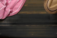 Towel. Scarf. Cover For Picnic. Straw Hat. Summer Travel Concept Elements. On Dark Wooden Table. Top View.