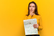 © Asier - Young european woman holding a map looking sideways with doubtful and skeptical expression.