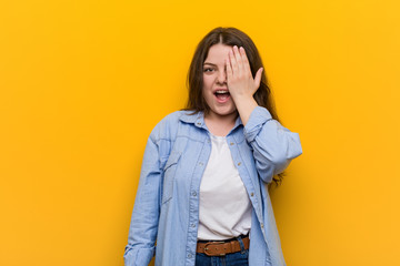 Wall Mural - Young curvy plus size woman having fun covering half of face with palm.