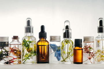 Transparent Bottles of essential oil with fresh herbs.