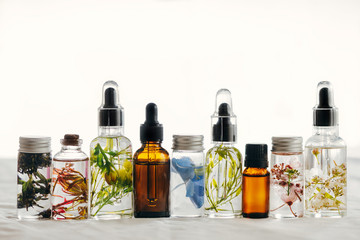 Transparent Bottles of essential oil with fresh herbs.