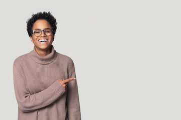 Smiling black girl in glasses point at copy space