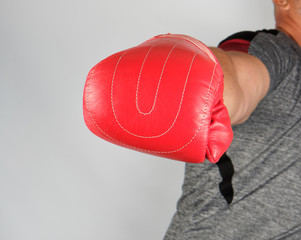 adult athlete in gray uniform and red leather glove strikes forward