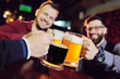 © Evgeniy Kalinovskiy - a group of young men's friends in a bar or pub drinking beer with glasses and watching football during the celebration of Oktoberfest
