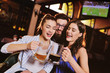 © Evgeniy Kalinovskiy - a group of friends - young guys and girls drinking beer, talking and smiling at the bar