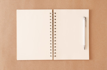 An empty notebook that has been left open and pen on an old brown background.