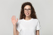 © fizkes - Smiling girl in glasses looking at camera wave hand studioshot