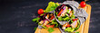 Tortilla with added ink cuttlefish wraps with chicken and vegetables on black background. Chicken burrito, mexican food. Banner