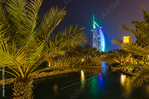 Cuadros en Lienzo Beautiful DUbai lit at night as a tour boat leaves a light trail behind