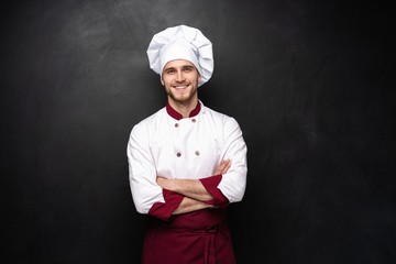 Wall Mural - Young male chef isolated on a black background.