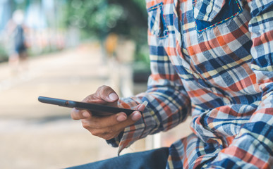 close up handsome man using hand typing mobile phones and touch screen working search with app devices outdoor in city with sunrise and building background.