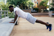 © twinsterphoto - Young African American man doing push up in city park. Male sporty person exercising outdoors