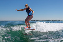 A Foil Board Being Ridden By A Woman Wake Surfer.