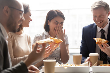 Wall Mural - Happy asian worker laugh hold slice eating pizza with colleagues