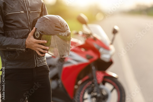 Fotografía Handsome motorcyclist wear leather jacket and holding helmet on the road