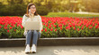 Happy girl talking on phone with laptop near blooming tulips