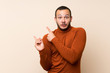 © luismolinero - Colombian man with turtleneck sweater frightened and pointing to the side