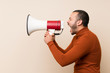 © luismolinero - Colombian man with turtleneck sweater shouting through a megaphone