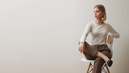 Fashionable girl in a white sweater and checkered pants . Natural lifestyle portrait of girl , emotional and fashion mood ,chic clothes and summer theme . Soft warm vintage color tone . Gold earrings