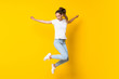 canvas print picture - Young woman jumping over isolated yellow wall