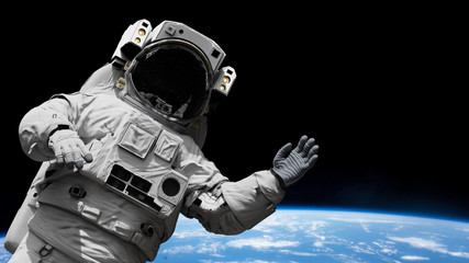 Wall Mural - astronaut waving during a spacewalk in orbit of planet earth
