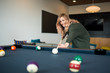 © Cavan Images - Woman preparing to take her shot during game of pool