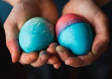 Close Up Of Child's Hands Holding Two Colored Easter Eggs.