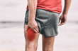 Hamstring pain pulled muscle on back thigh painful red area athlete man massaging sports injury fitness cramp muscles.