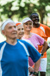 © LIGHTFIELD STUDIOS - selective focus of cheerful retired african american man standing with hands on hips with pensioners in sportswear
