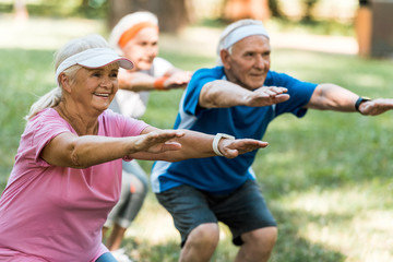 Wall Mural - selective focus of happy multicultural senior people doing sit ups on grass