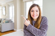 © Krakenimages.com - Beautiful young woman at home cheerful with a smile of face pointing with hand and finger up to the side with happy and natural expression on face