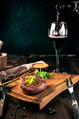 Wall Mural - Grilled ribeye beef steak with wine, knife and fork on a wooden Board. Whole roast piece of meat, rustic style