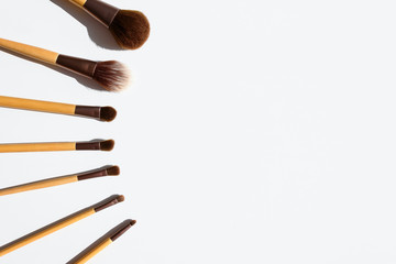 Top view of make up brushes set, arranged in a line. Natural accessories with bamboo wood handles. Copy space on white table.