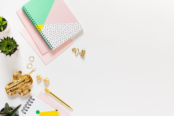 Flat lay desk table. Workspace with modern notebooks, stationery, succulents and jewelry on white table. Top view, copy space.