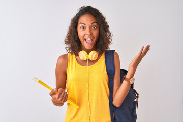 Poster - Brazilian student woman wearing backpack holding notebook over isolated white background very happy and excited, winner expression celebrating victory screaming with big smile and raised hands