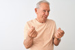 © Krakenimages.com - Senior grey-haired man wearing striped t-shirt standing over isolated white background doing money gesture with hands, asking for salary payment, millionaire business