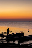 Fototapeta Sypialnia - Silhouettes of fishermen and boats at the Port of Ahtopol, Black Sea Coast, Bulgaria at sunrise
