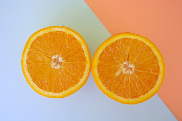 2 slices of orange placed on pop art sliced background, flat lay with pink and blue colors