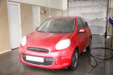 Canvas Print - Worker cleaning automobile with high pressure water jet at car wash