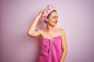 Sticker - Young beautiful woman wearing towel and bath hat after shower over pink isolated background confuse and wonder about question. Uncertain with doubt, thinking with hand on head. Pensive concept.