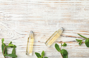 Flat lay composition with mint essential oil and space for text on white wooden background