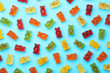 Delicious bright jelly bears on blue background, flat lay