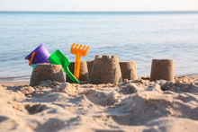 Little Sand Figures And Plastic Toys On Beach Near Sea