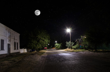 Wall Mural - full moon over quite village at night. beautiful night landscape of old town street with lights. rus