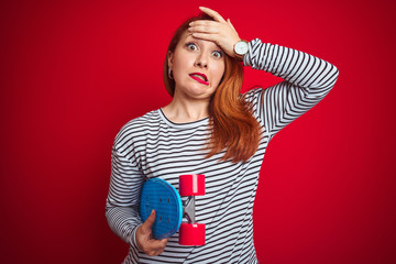 Sticker - Young redhead student woman holding skate over red isolated background stressed with hand on head, shocked with shame and surprise face, angry and frustrated. Fear and upset for mistake.