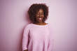 © Krakenimages.com - Young african afro woman wearing sweater standing over isolated pink background winking looking at the camera with sexy expression, cheerful and happy face.